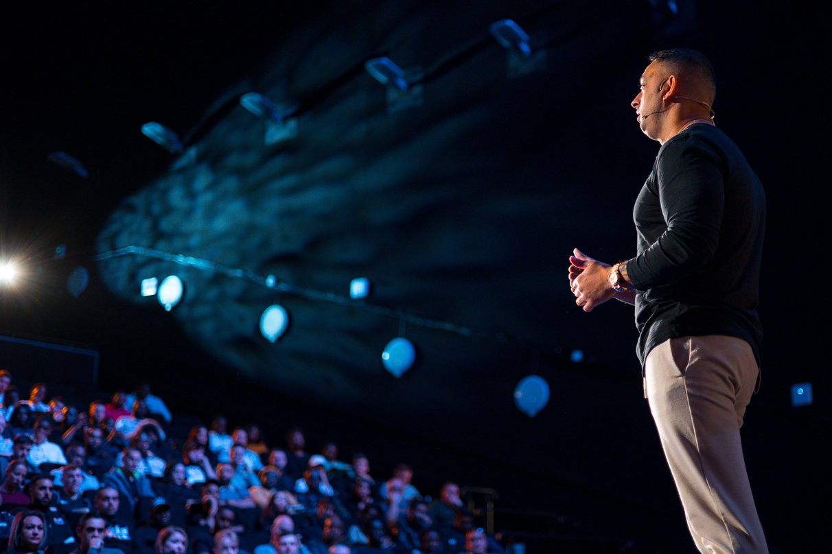 Ste Hamilton speaking on stage to a packed audience